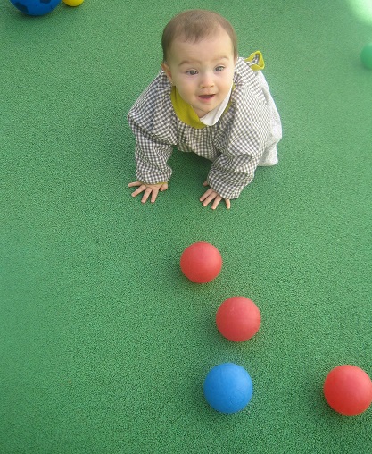 Bebé gateando tras pelotas de colores
